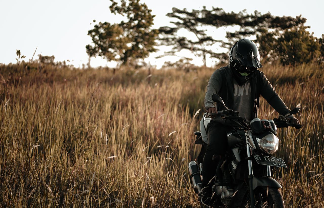 a motorcyclist navigates through a grassy field on an autumn day showc