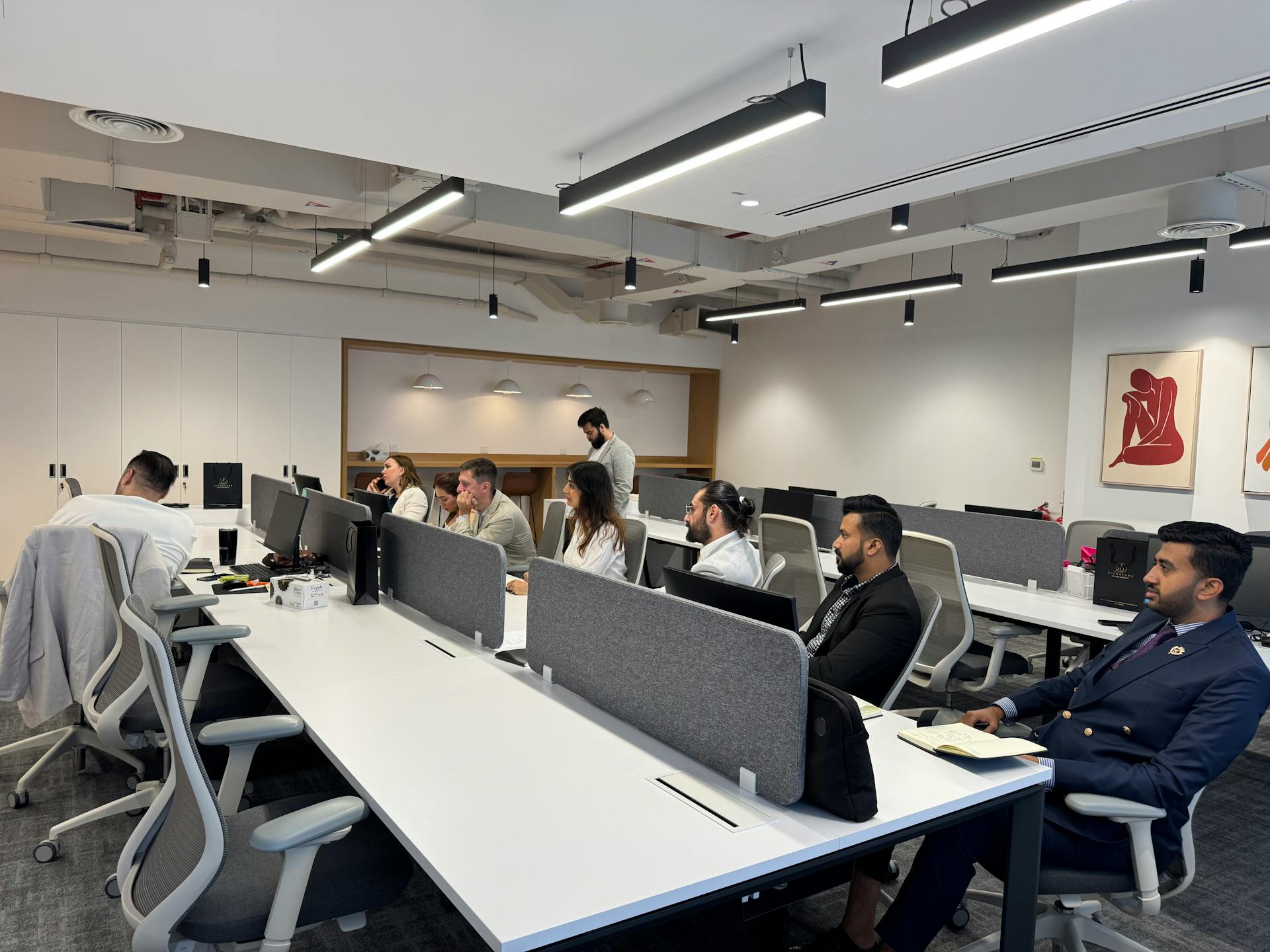 Diverse team working in a modern office setting with computers and collaborative spaces.