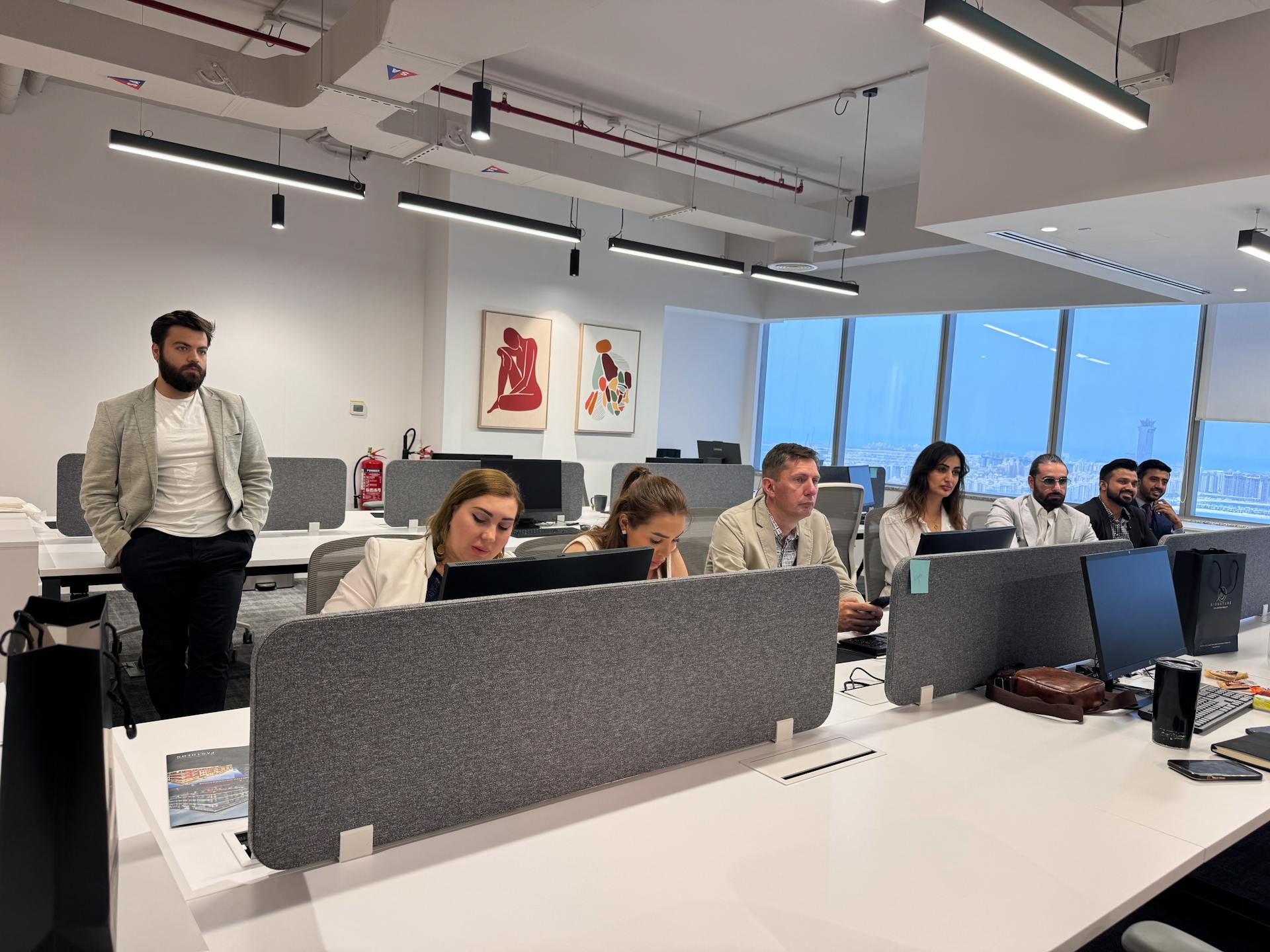 Team of professionals working in a modern office setting with computers and open workspace.