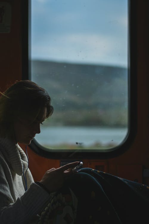 Woman in White Cardigan Sitting Near Window