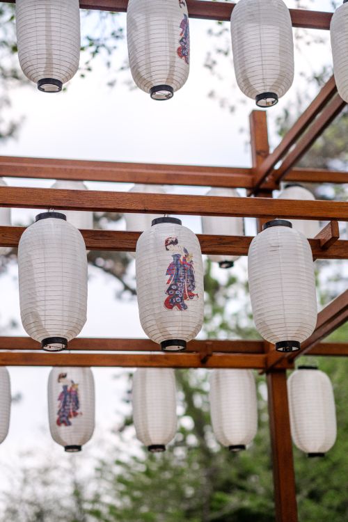 Free Traditional Japanese paper lanterns under a wooden pergola, set against a serene outdoor backdrop. Stock Photo