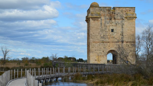 A scenic view of a historic tower and boardwalk in Saint-Laurent-d'Aigouze, Occitanie, France.