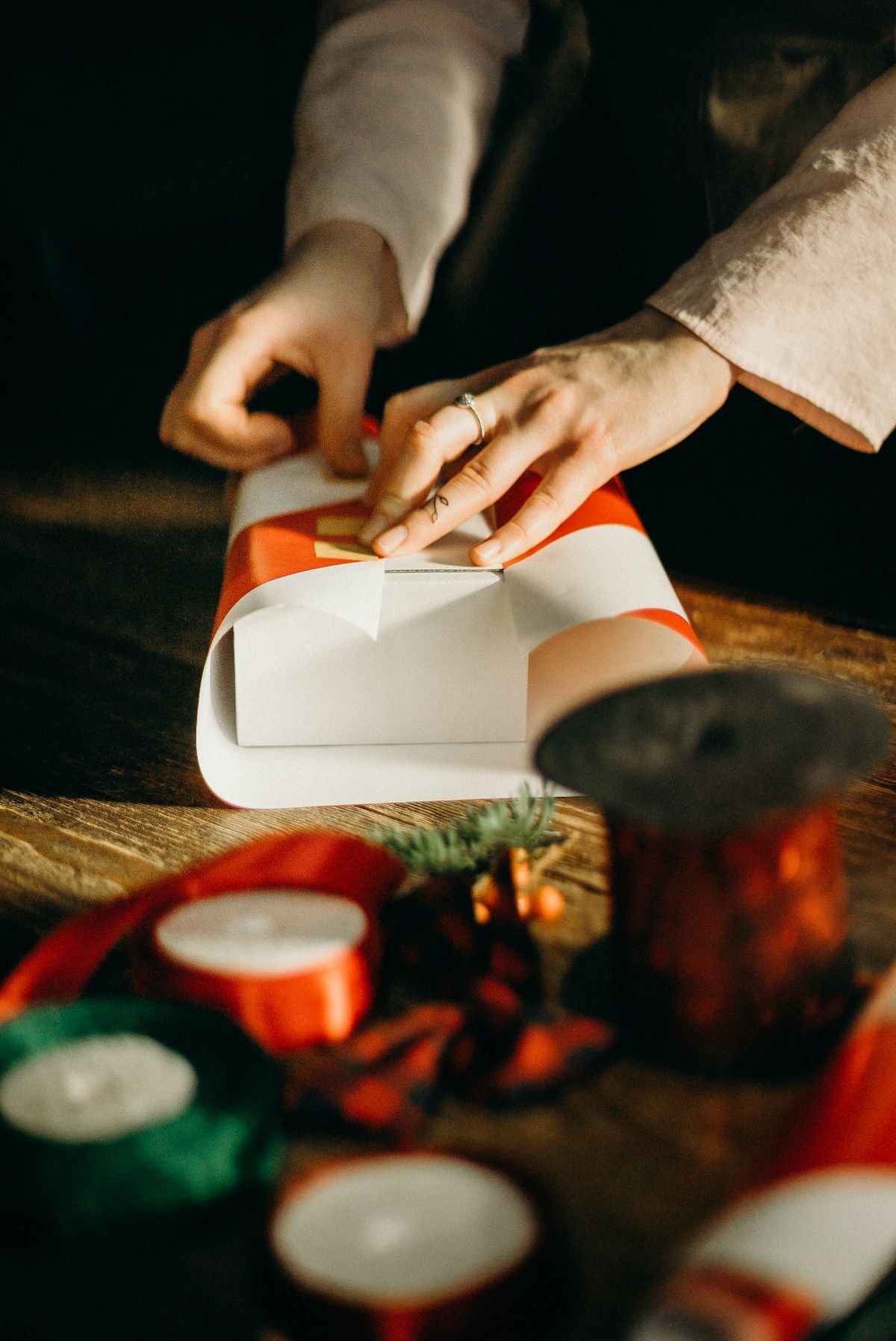 Person wrapping a Christmas gift with red ribbon