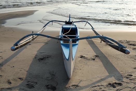 Outrigger canoe on a sandy beach in the Philippines during daytime.