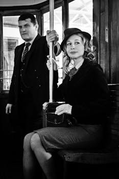 A vintage-themed black and white photo of two adults on a tram, evoking nostalgic vibes.