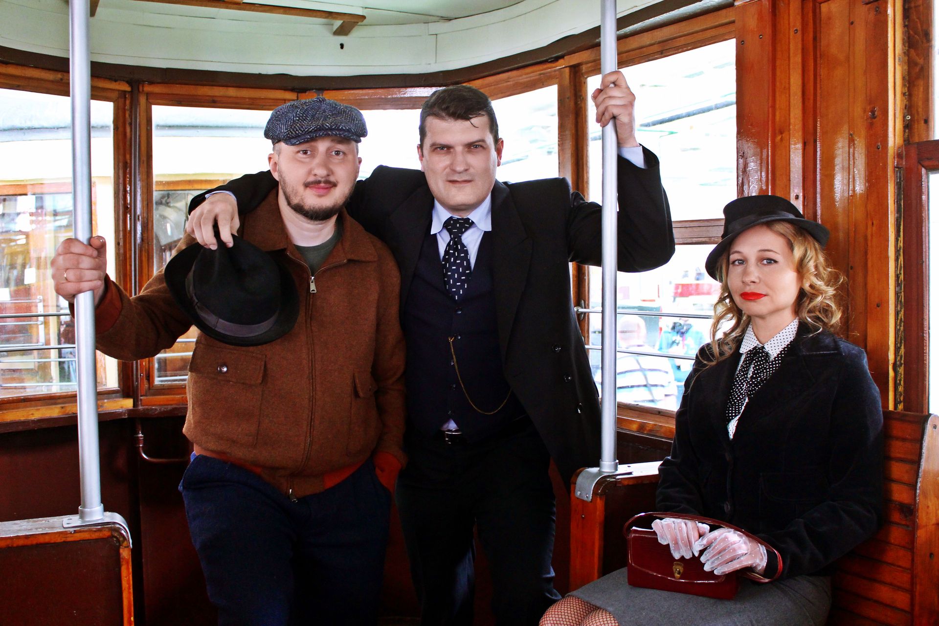 People in vintage 1940s-style clothing riding a classic tram together