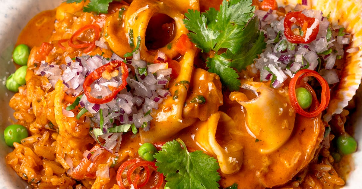 A close-up photo of a traditional Spanish paella dish with saffron-colored rice, seafood, and vegetables in a large pan.