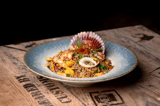 Delicious seafood fried rice garnished with shellfish, presented elegantly on a rustic table.
