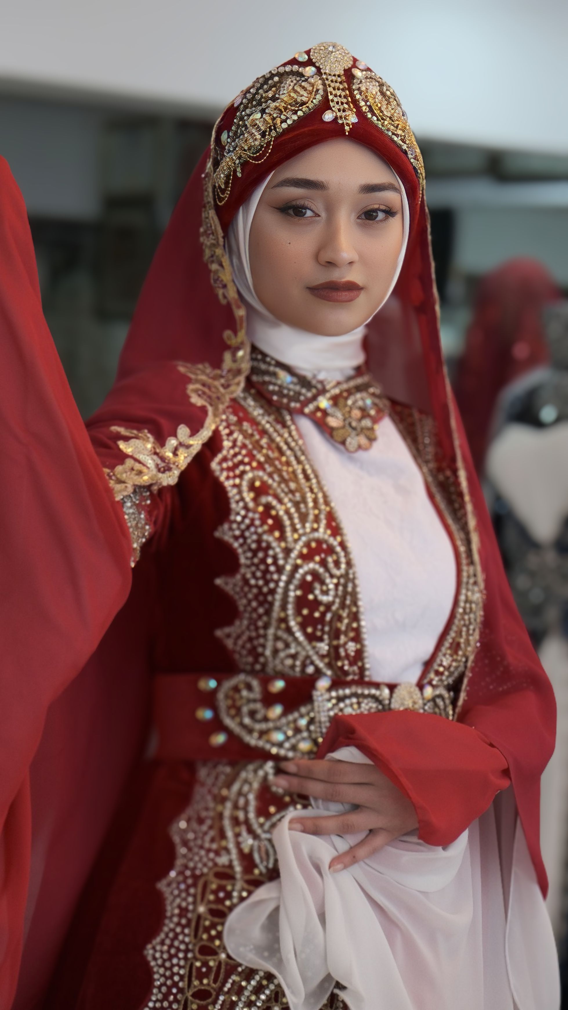 Portrait of a woman in a traditional ornate red bridal gown with intricate beadwork.