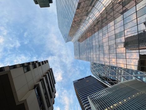 Looking up at modern skyscrapers in La Défense, Paris, against a blue sky.