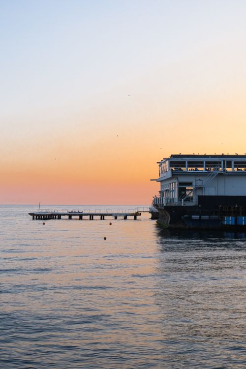 Free Tranquil seaside sunset with a wooden pier extending into calm waters. Stock Photo