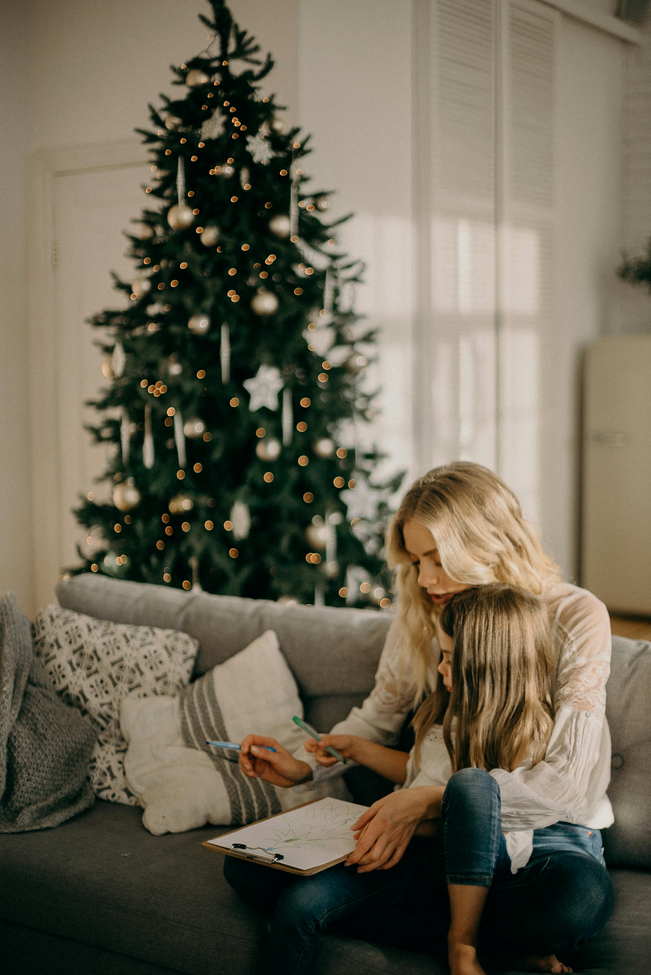 girl sitting on woman s lap while holding pen and paper