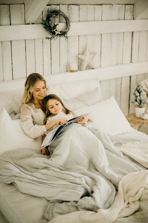 Mujer Y Niña Acostada En La Cama Mientras Sostiene El Libro