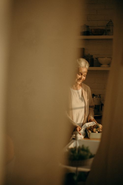 Free Senior woman cooking turkey in a warmly lit kitchen, ready for Thanksgiving celebration. Stock Photo