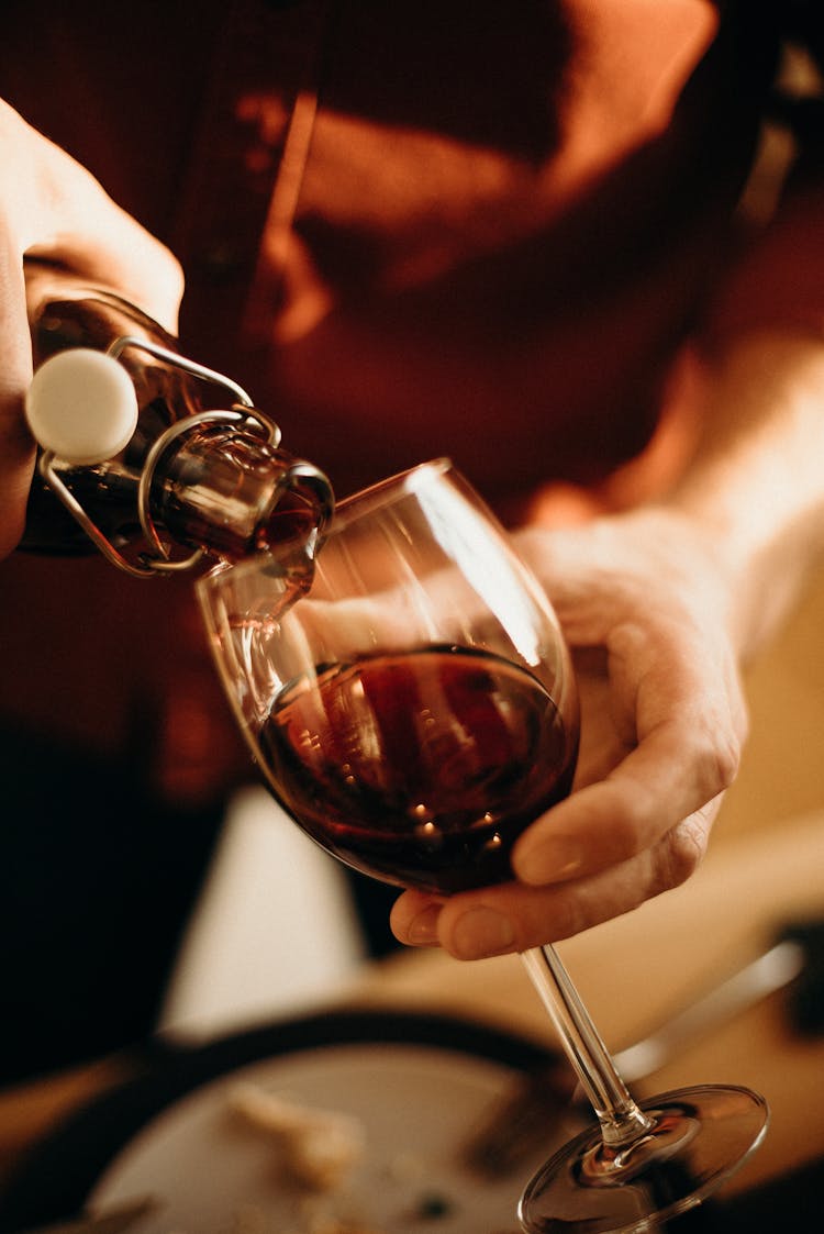 Person Pouring Wine On Wine Glass