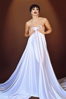 Striking portrait of a woman in white fabric against a warm backdrop, showcasing elegance and style.