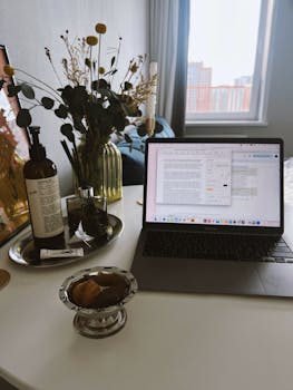 Elegant home office setup with laptop, plants, and decor on a table.