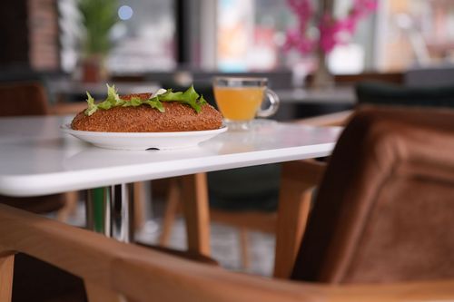Free A simit with lettuce on a plate and a cup of tea on a cozy café table. Stock Photo