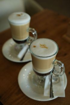 Close-up of two frothy lattes on a wooden table, perfect for a cozy coffee break.