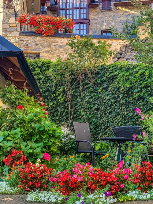 Free Beautiful garden patio featuring vibrant flowers and rustic stone building. Stock Photo
