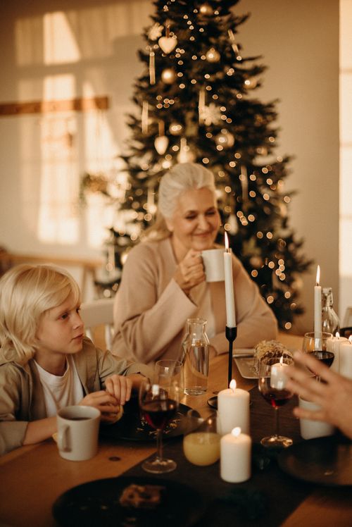Free Warm family gathering around Christmas tree with candles and drinks, celebrating togetherness. Stock Photo