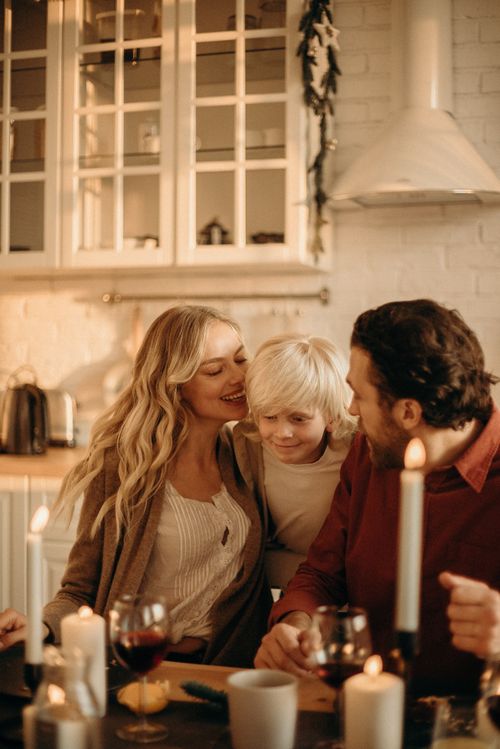 Free A family enjoying a festive dinner in a warm, candlelit kitchen setting, fostering togetherness. Stock Photo