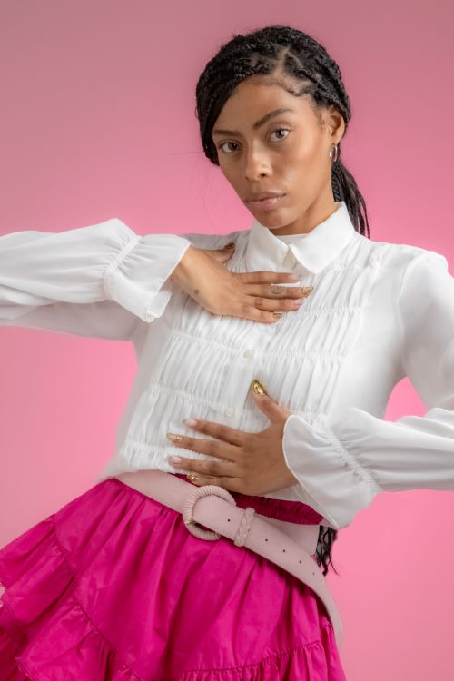 Free Elegant portrait of a woman in a white blouse against a pink background. Stock Photo