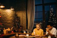 两个孩子用烛光在室内装饰姜饼饼干，营造出舒适的假期氛围