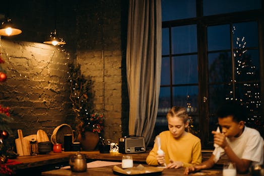 两个孩子用烛光在室内装饰姜饼饼干，营造出舒适的假期氛围