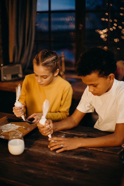 Ragazza E Ragazzo Che Decorano I Biscotti