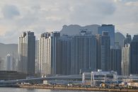Cityscape featuring towering high-rise buildings against a mountainous backdrop.