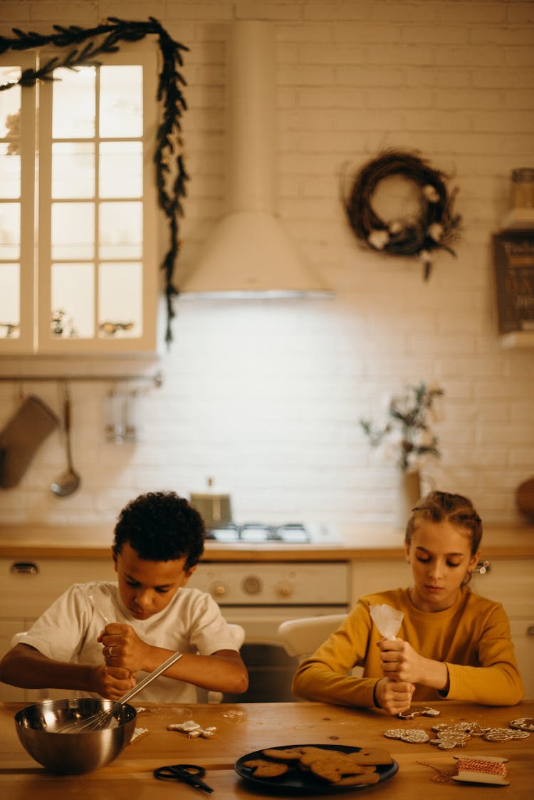 Boy And Girl Piping Icing On Cookies