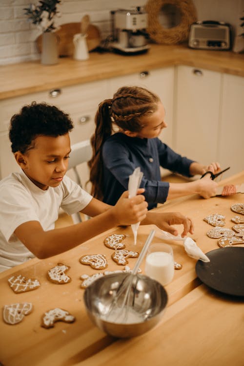 Free Two Kids Putting Cream on Cookies Stock Photo