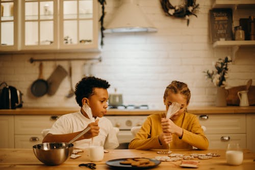 Two Kids Puting Cream On Pastry