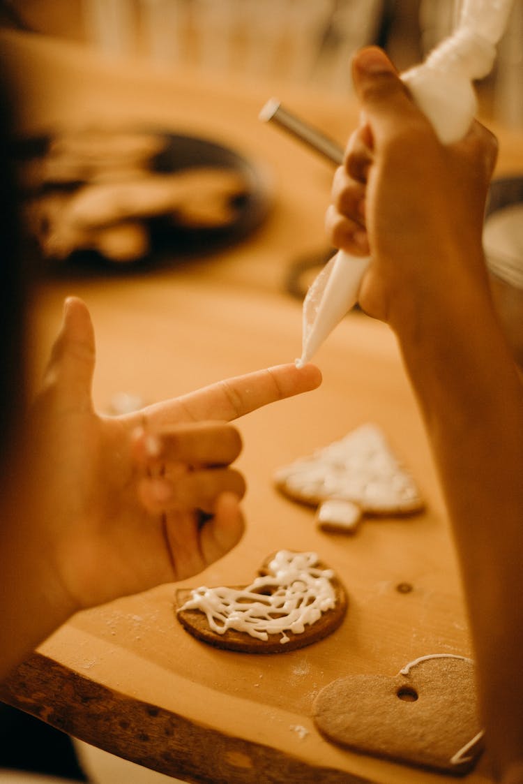 Person Piping Icing On His Finger