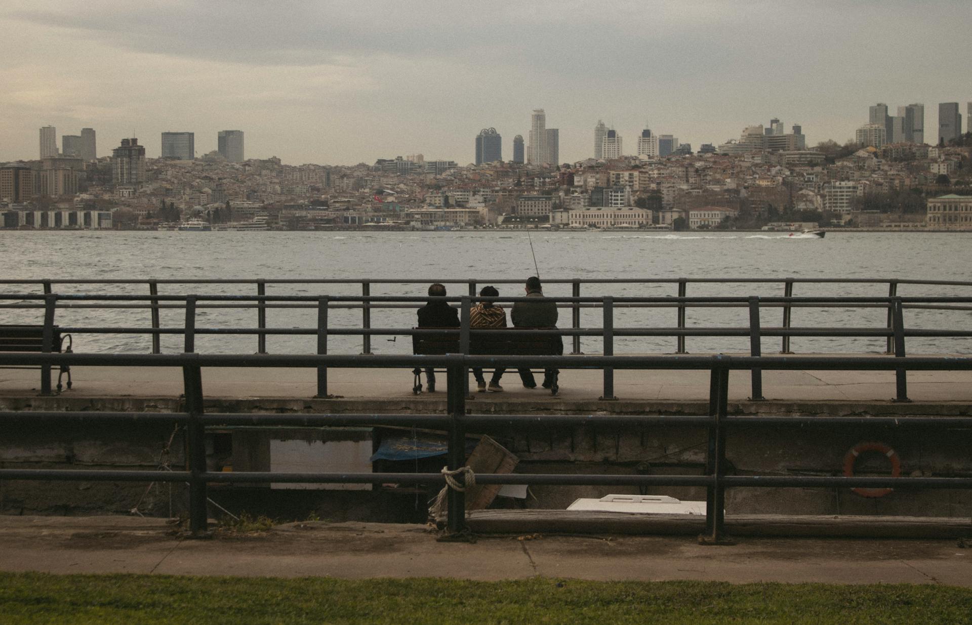 Two individuals enjoying a calm moment by the waterfront overlooking a city skyline.