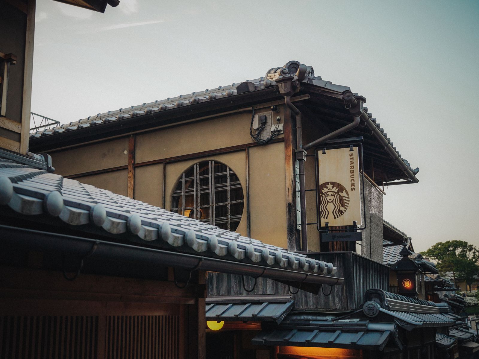 Blend of traditional Kyoto architecture and modern cafe sign, captured at twilight.