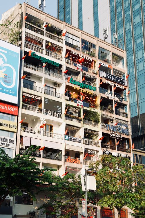 Free A lively apartment building in Ho Chi Minh City adorned with colorful cafe signs and flags. Stock Photo