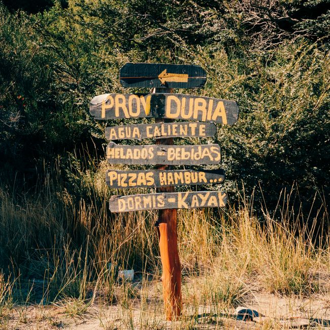 A rustic wooden signpost in San Carlos de Bariloche, Argentina, surrounded by nature.