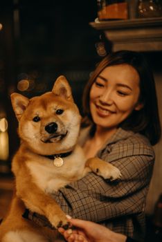 一位女士在舒适的室内，深情地抱着她的柴犬