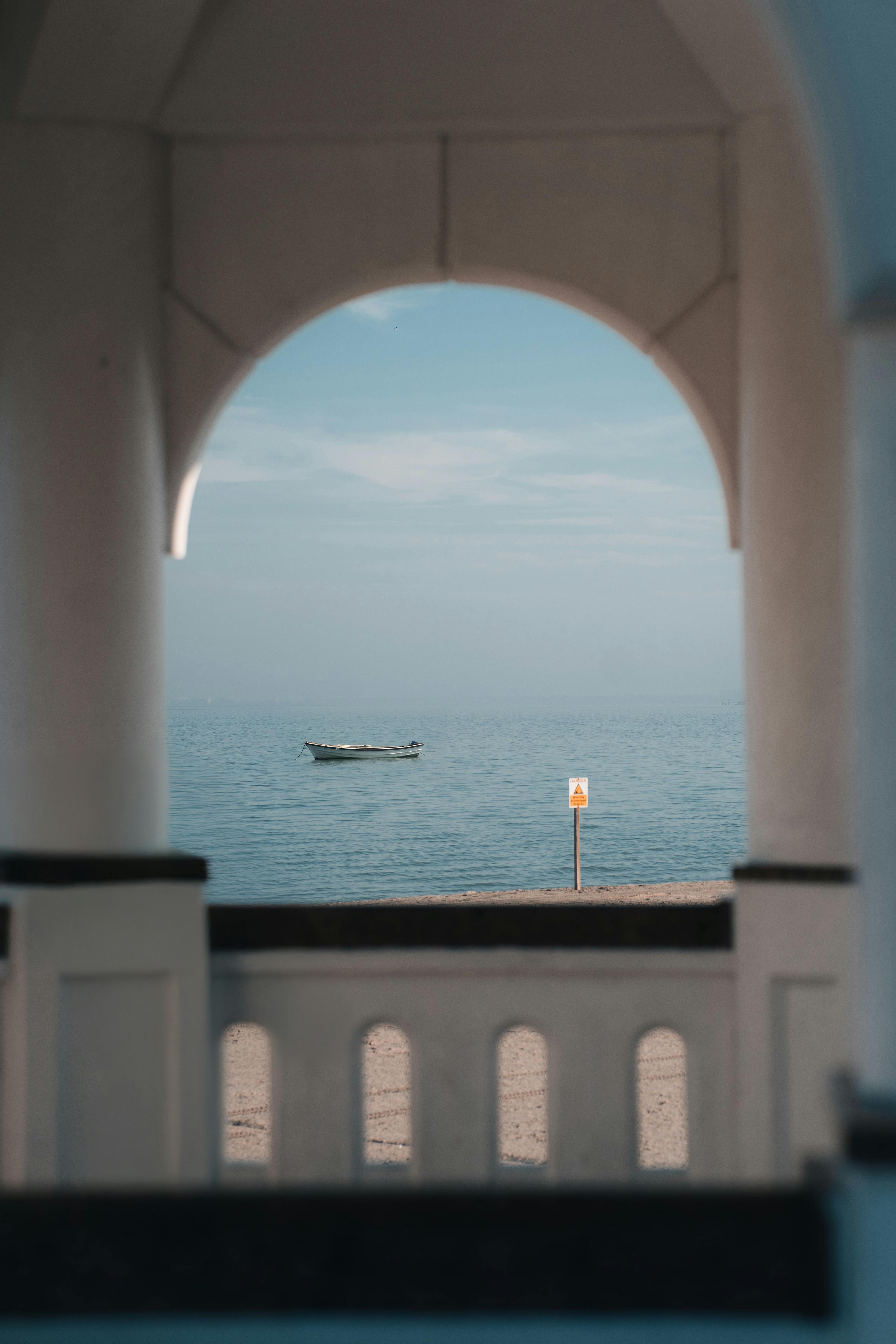 Serene ocean view framed by an archway with a lone boat in Corpus Christi, Texas.