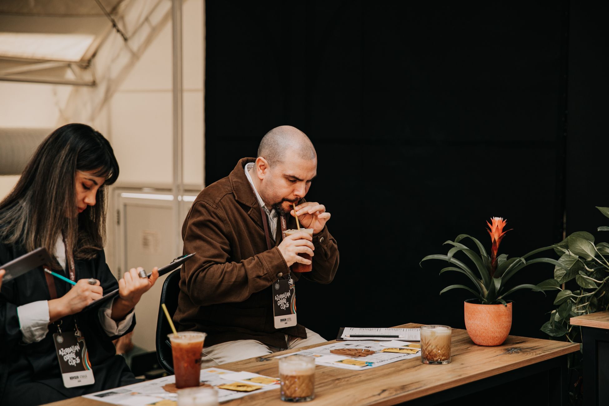 Judging panel tasting drinks at a Baku event with close-up focus on evaluation process.
