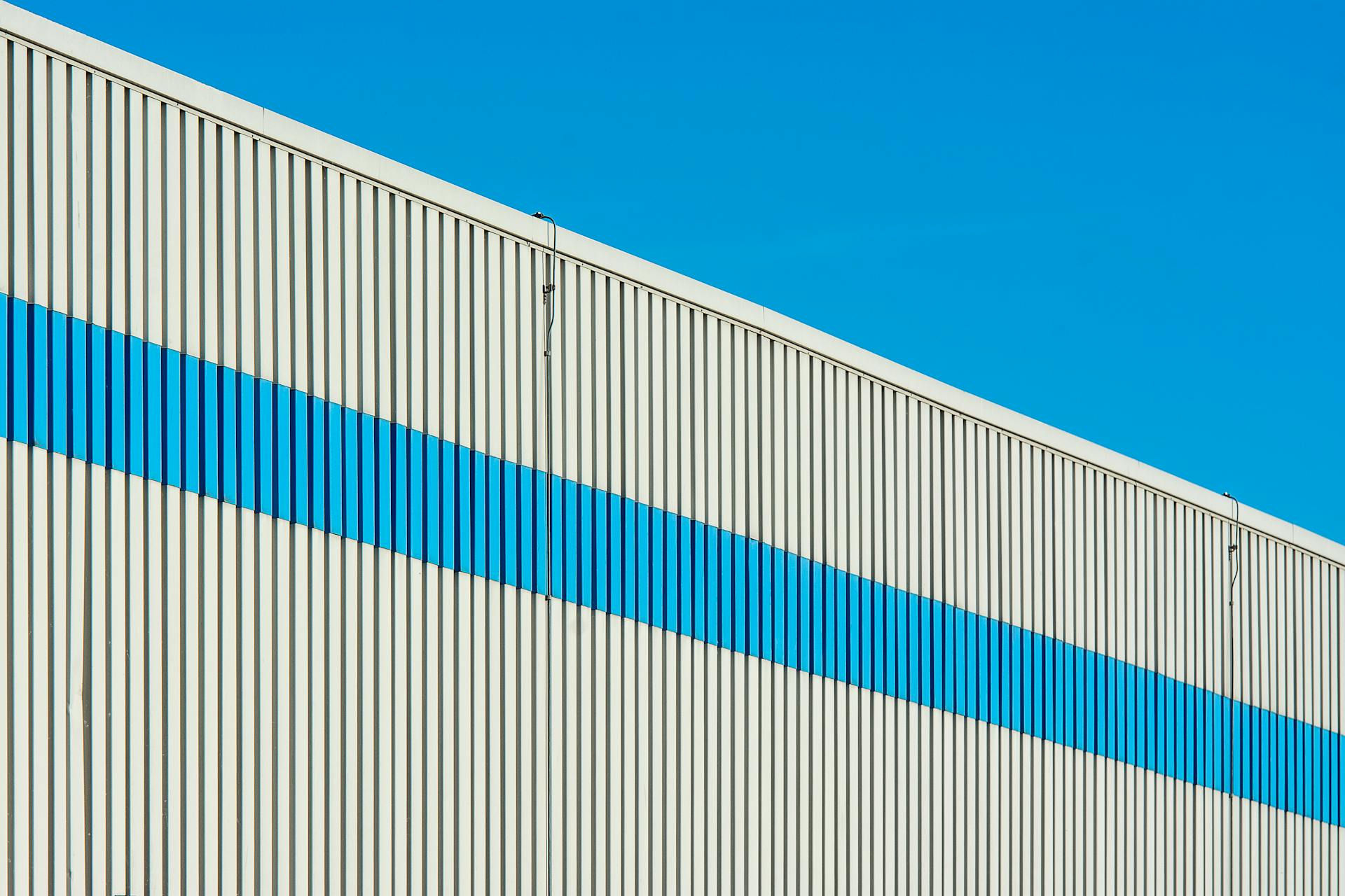 A modern industrial building facade featuring a distinctive blue stripe on a sunny day.