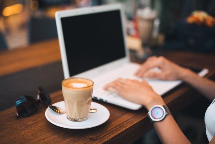A person typing on a laptop beside a coffee on a wooden table -- photo by Chevanon Photography on Pexels