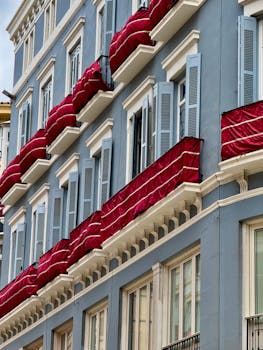 Elegant building facade in Málaga, Spain, featuring vibrant red awnings and classic Mediterranean architecture.