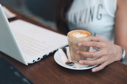 Close-up of Woman Holding Coffee Cup on Table