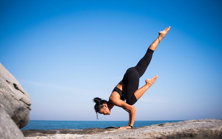 Low Angle View Of Woman Relaxing On Beach Against Blue Sky