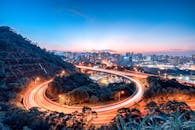 黄昏时分，蜿蜒的高速公路亮起灯火，捕捉到了城市生活的动态，与城市天际线的壮丽景色相映成趣