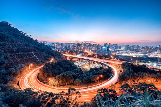 黄昏时分，蜿蜒的高速公路亮起灯火，捕捉到了城市生活的动态，与城市天际线的壮丽景色相映成趣