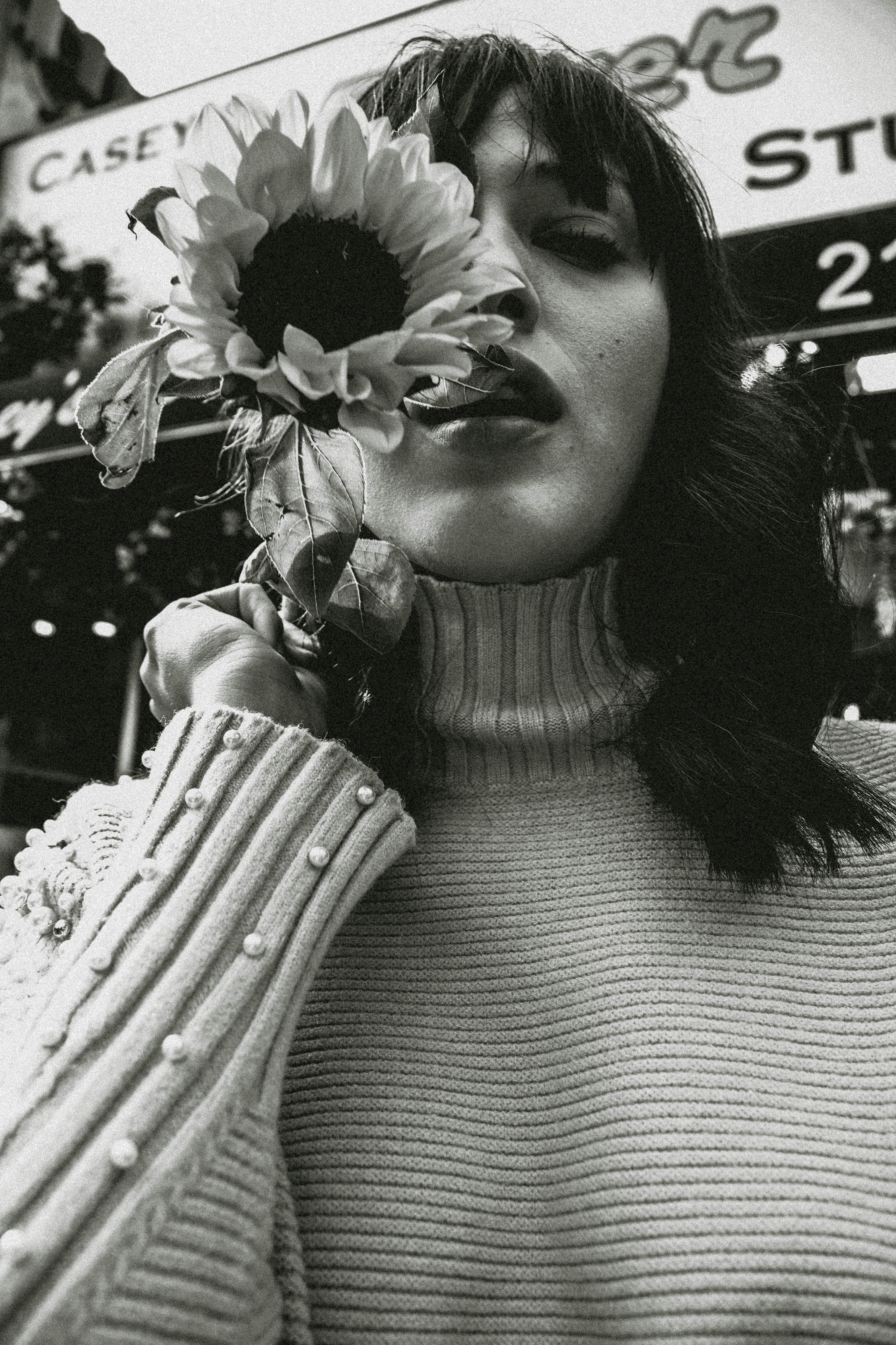 greyscale photo of woman holding sunflower